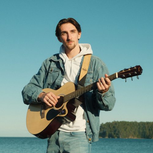 2023-09-30 Photo of Ryan Palm by Cam Sim – Guitar, Water, & Sky Head-shot profile photo of Ryan Palm with a blue sky background over water